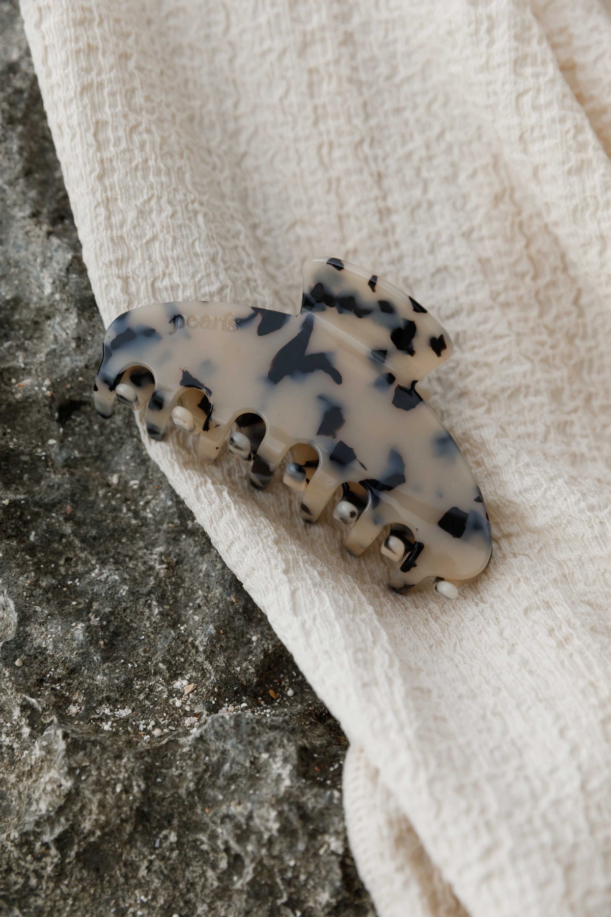 Tortoiseshell acetate claw clip resting on stone and linen